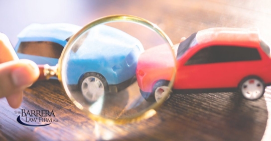 Two toy cars head to head with a magnifying glass on them.
